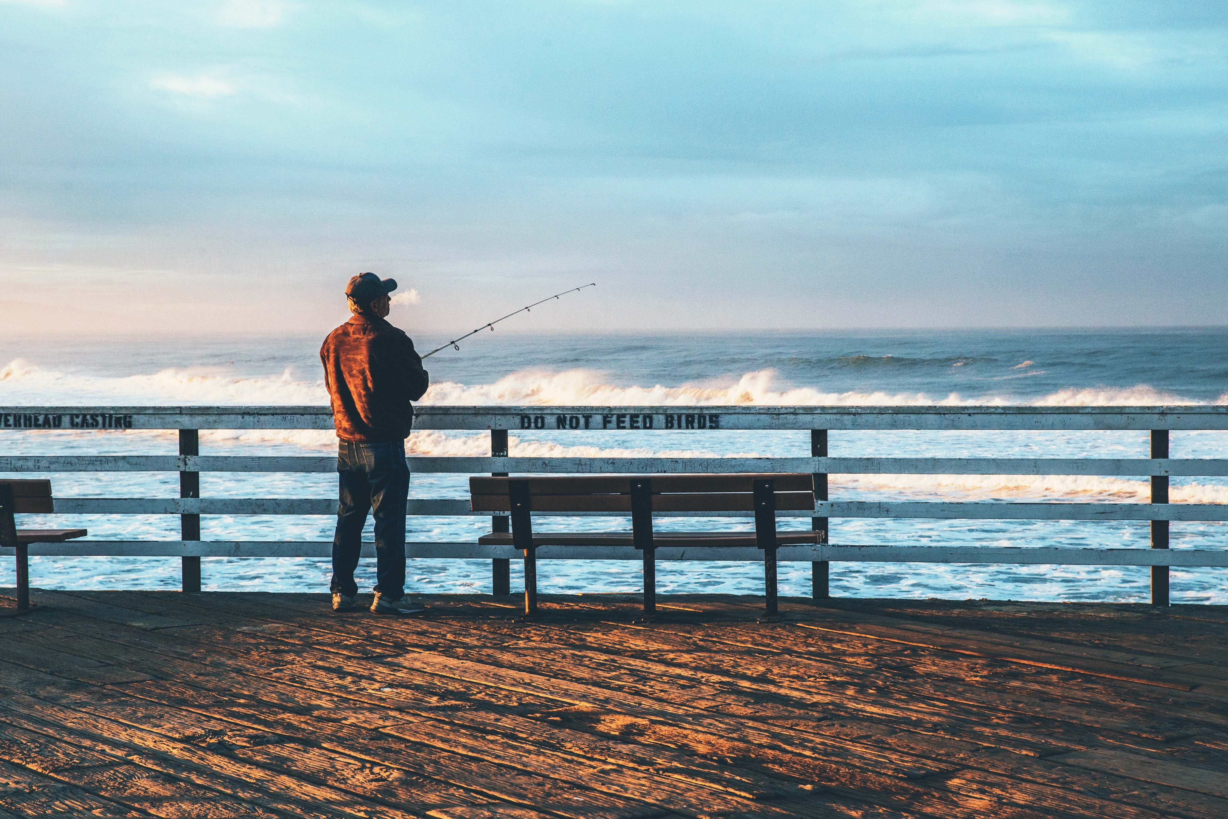 a man fishing off of the pier in pismo beach