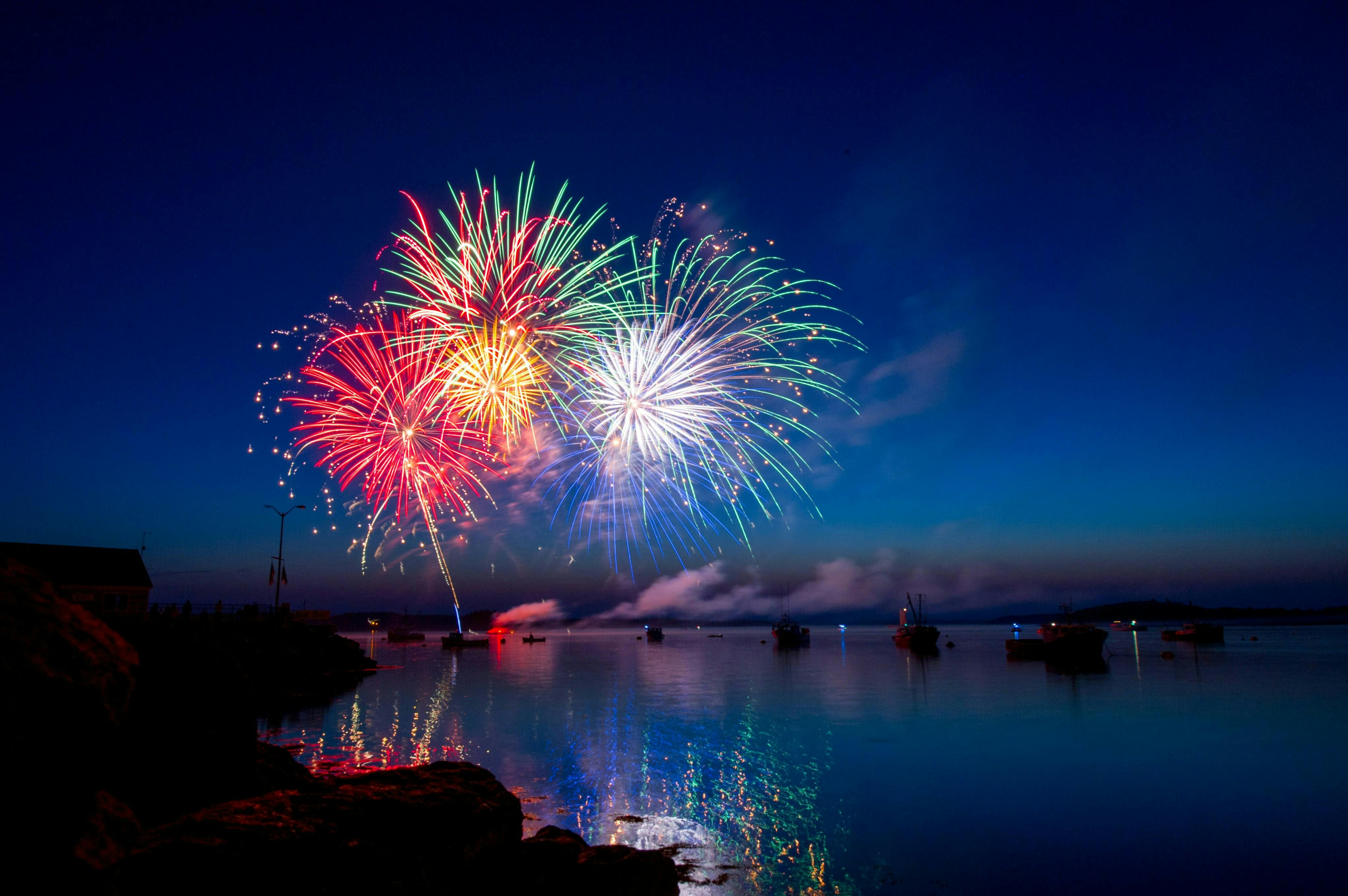 Fireworks over water with boats.