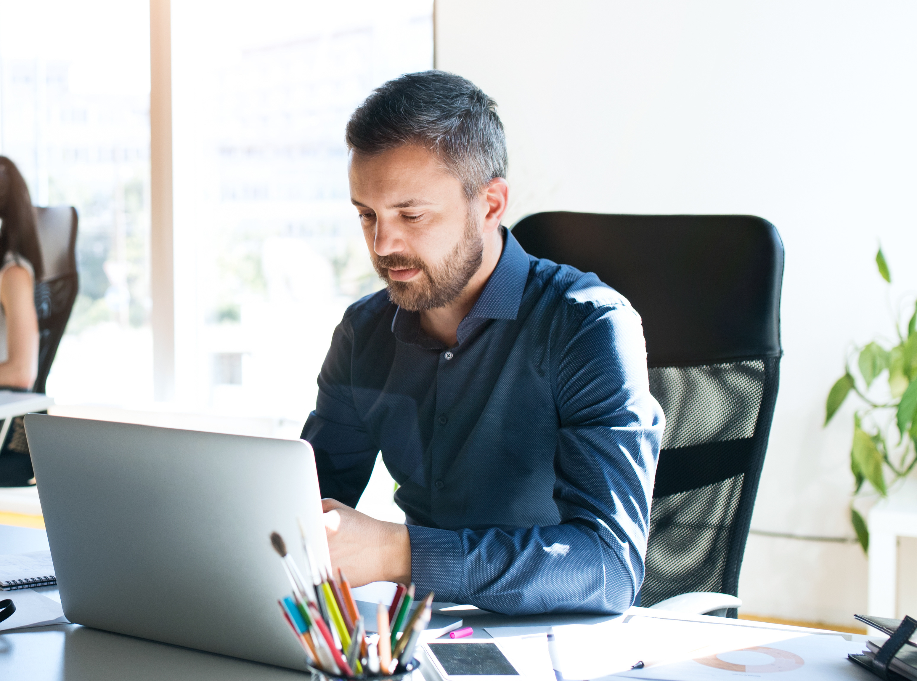 man sits at desk while looking at his laptop