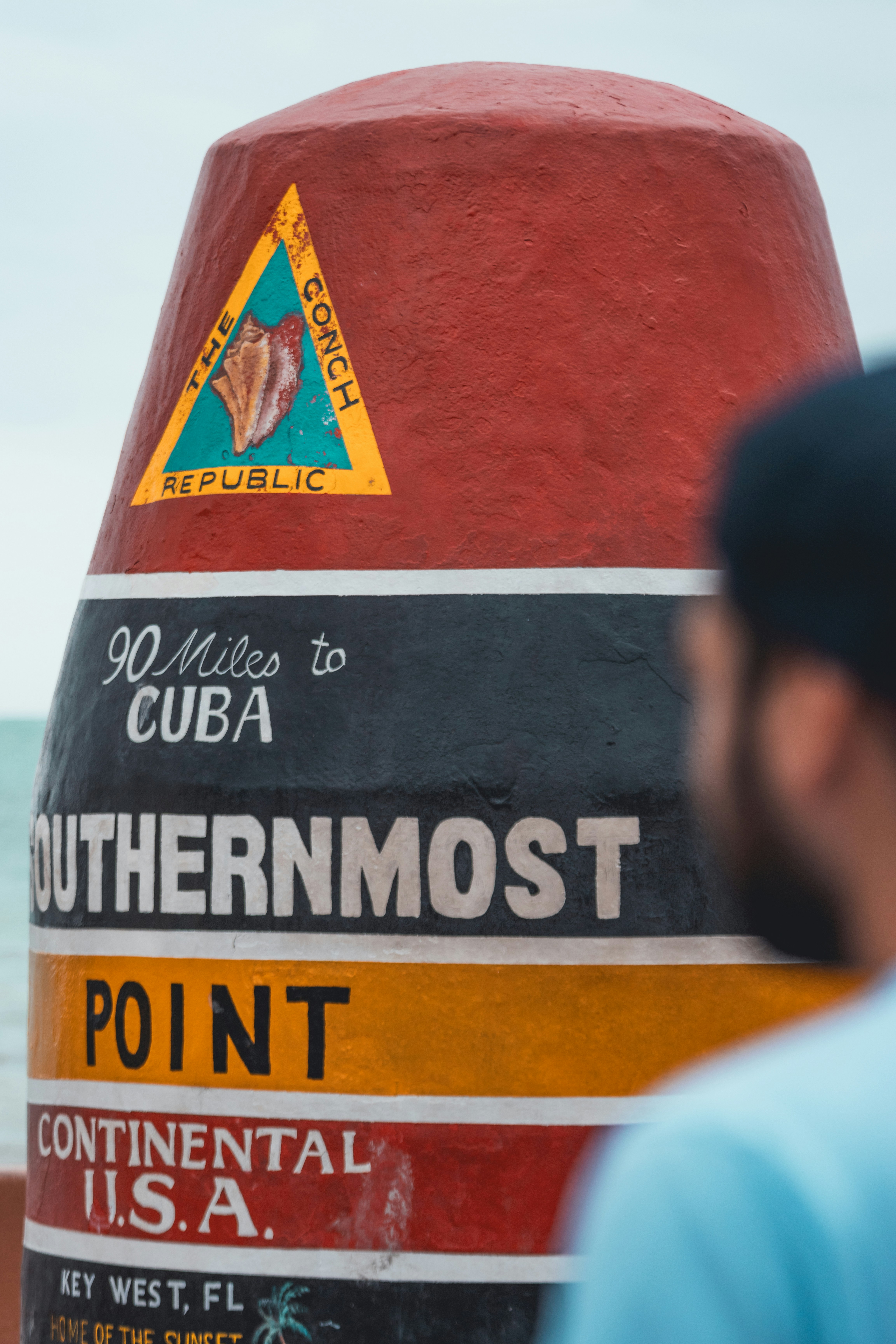 Key West  buoy with a man to the right of the image.