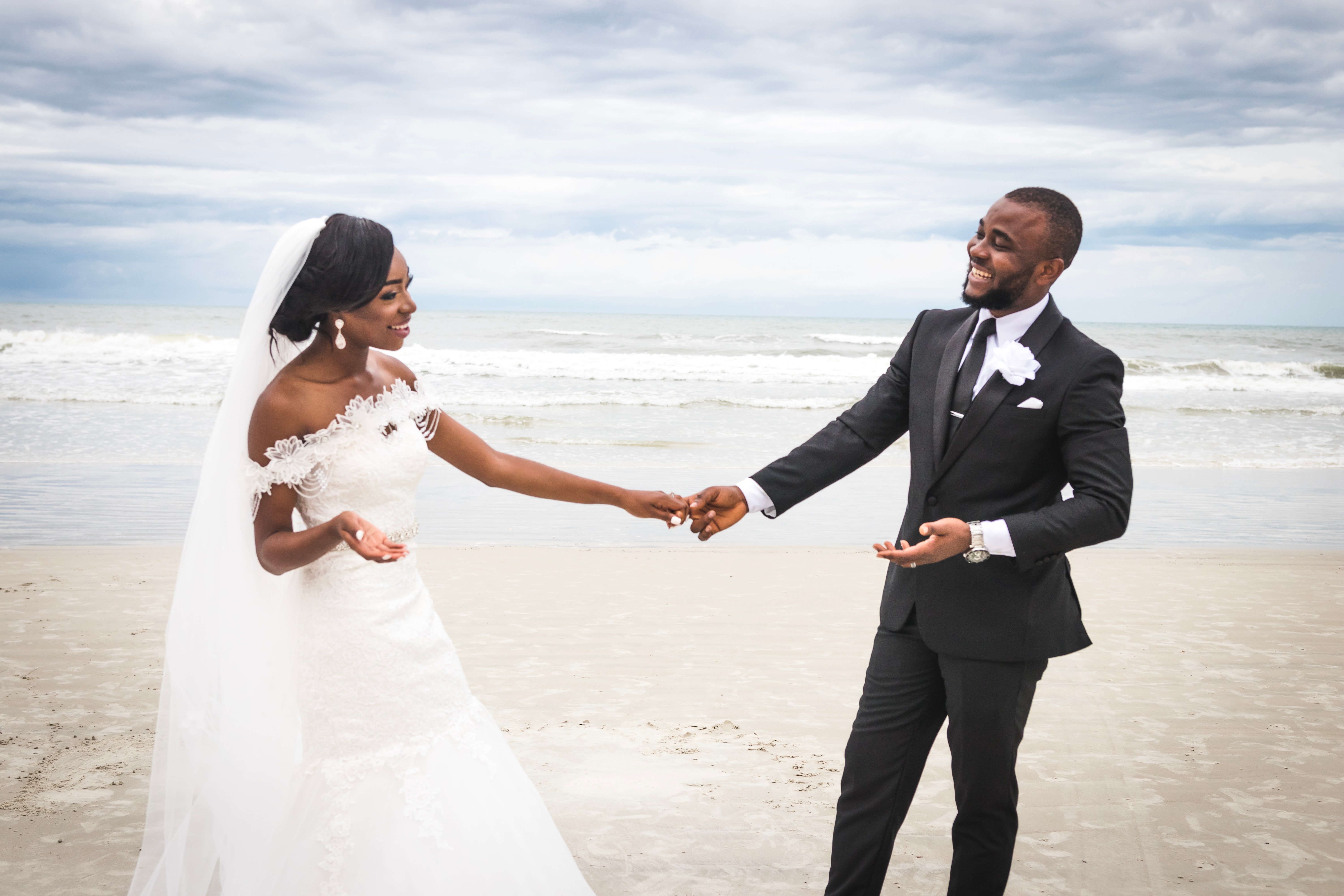 bride and groom holding hands at the beach